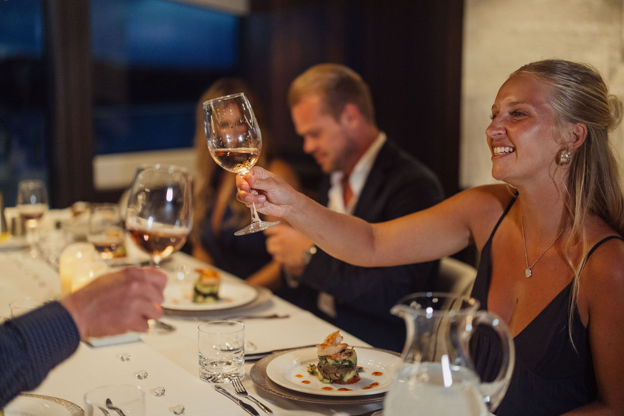 Guest raising wine glass at dinner on M/Y Lio Black Knight Sunseeker 95 — charter dining